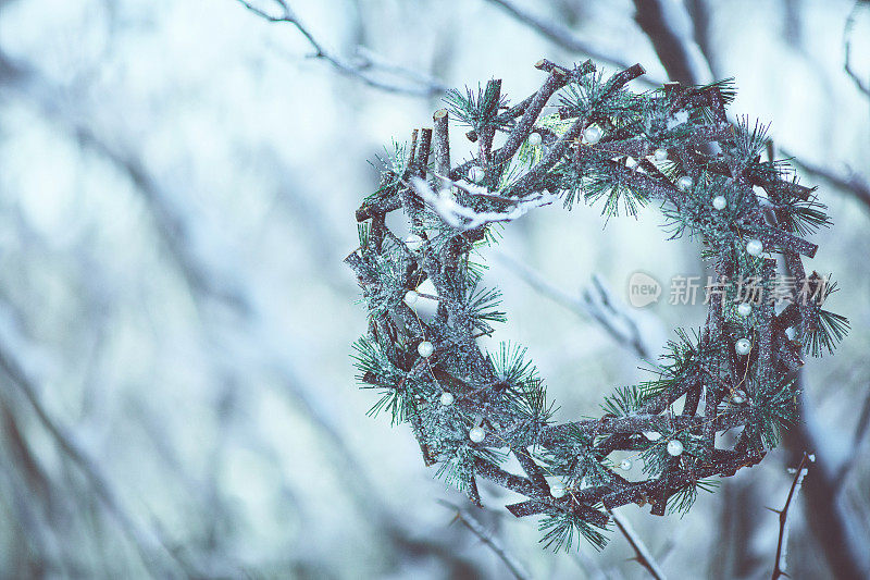 乡间的花环挂在户外被雪覆盖的树枝上