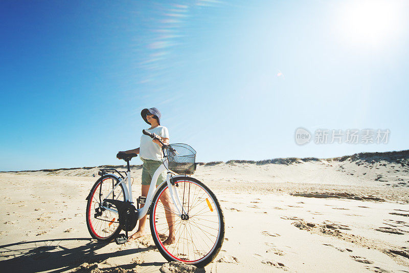 年轻的成年女子骑着自行车在海滩上