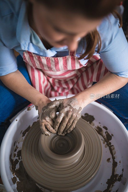 在艺术工作室里，年轻的妇女们在陶轮上制作陶器。