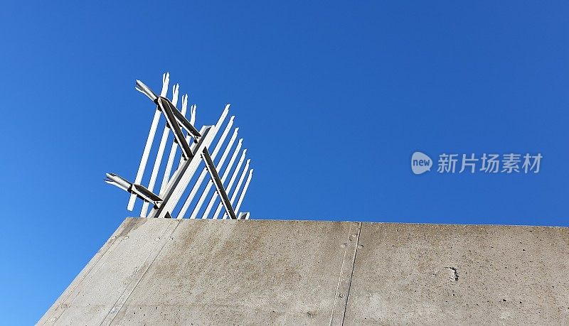 混凝土墙与尖刺金属栅栏对抗蓝天和复制空间