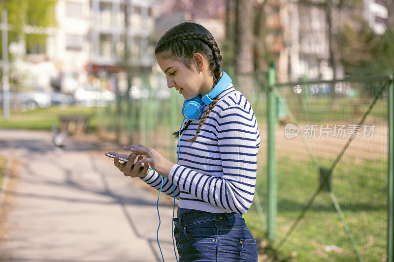 美丽的年轻女孩在户外使用她的手机