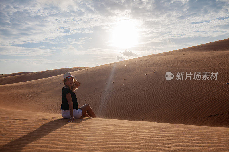 一个女人赤脚站在沙漠的沙丘上