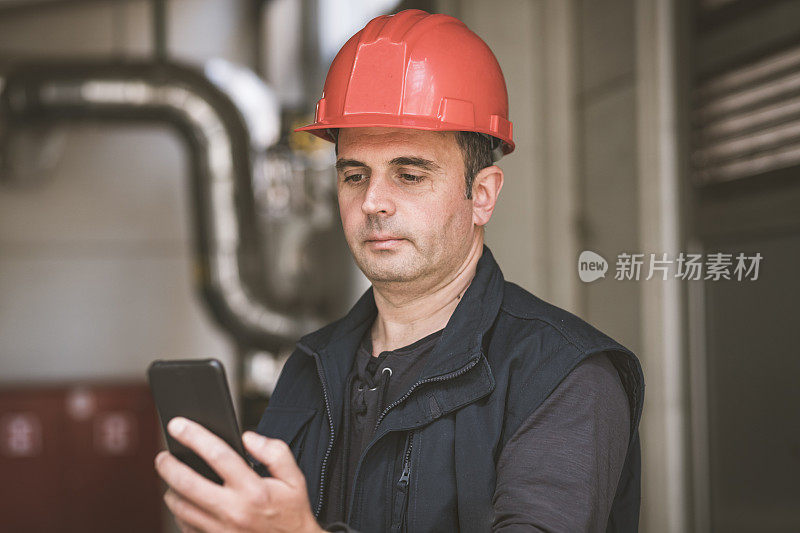 在工厂里使用手机的男性技术员