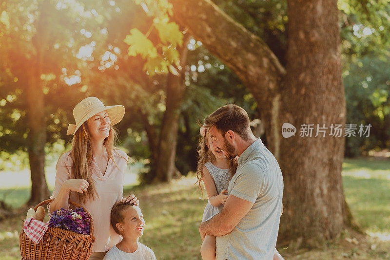 快乐的一家人抱着孩子，欢笑着，在大自然中享受夏日