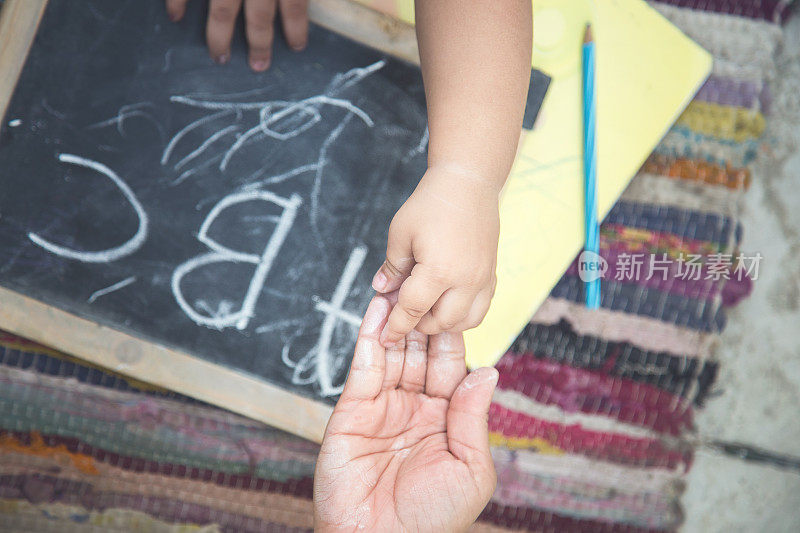 印第安母亲和女婴在黑板上用粉笔写字和画画