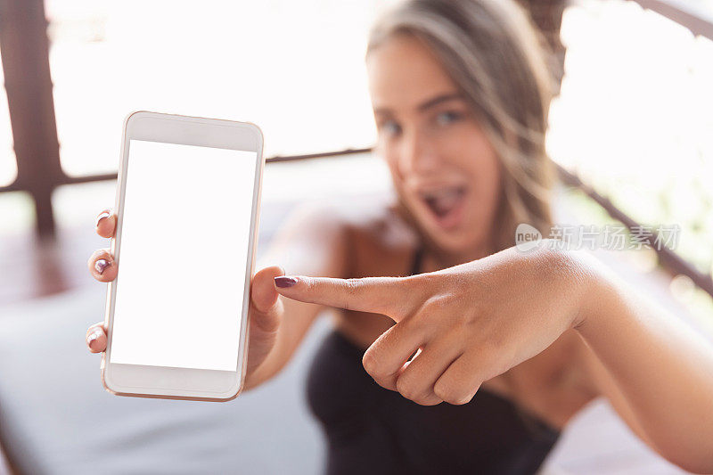 一个惊讶的女人展示了一个空白的智能手机屏幕