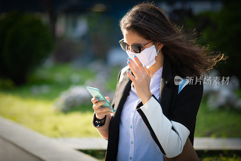 女人戴着保护面罩看手机