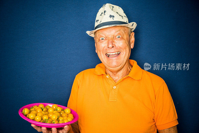快乐有趣的老人拿着一盘西红柿
