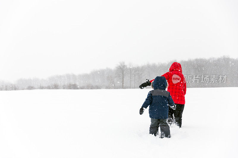 母亲和儿子走在田野在冬天暴风雪期间