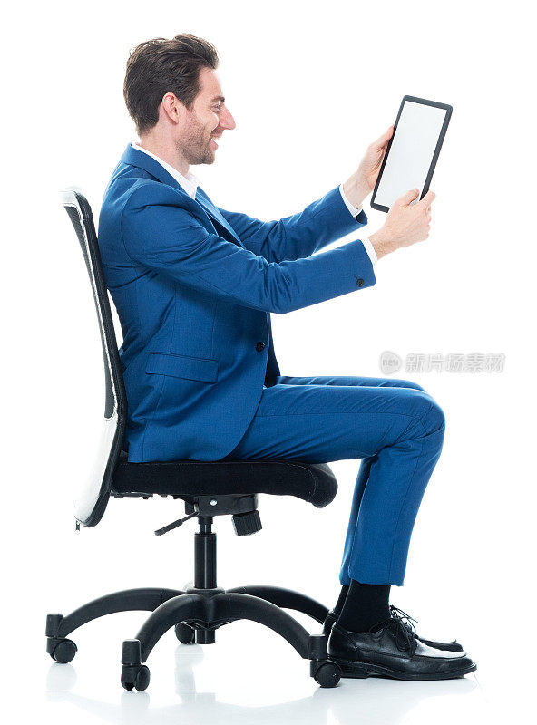 白人男性商务人士坐着，穿着西装，使用触摸屏