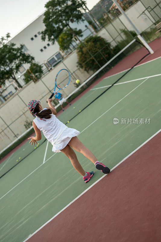 一个女孩和她的网球教练在硬地打网球，正手和反手投篮