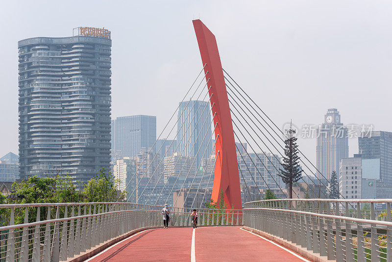 成都天府绿道上的人们以摩天大楼和红色电缆桥为背景