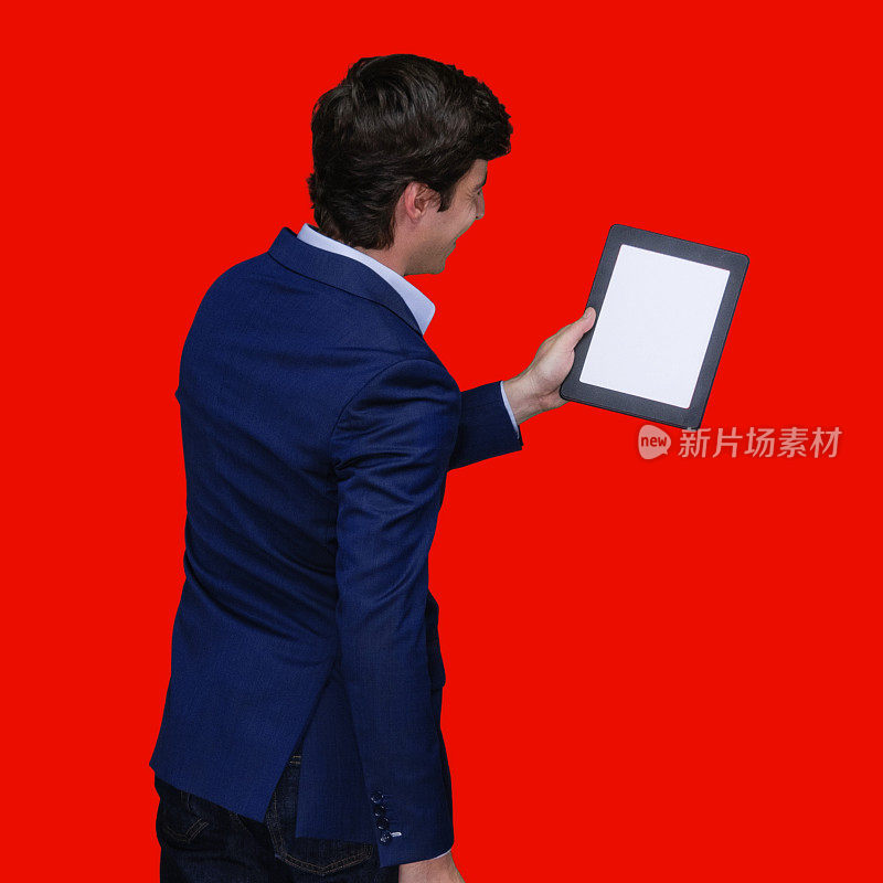 白人年轻男性穿着衬衫站在有色背景前使用数码平板电脑