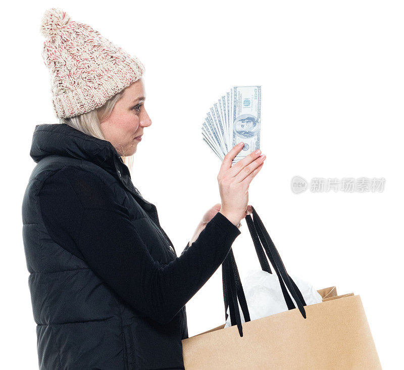 身穿马甲，手持钞票的女性购物狂站在白色背景前