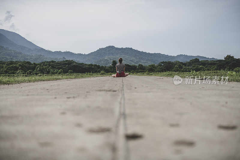 独自的旅行者独自坐在一条安静的路上