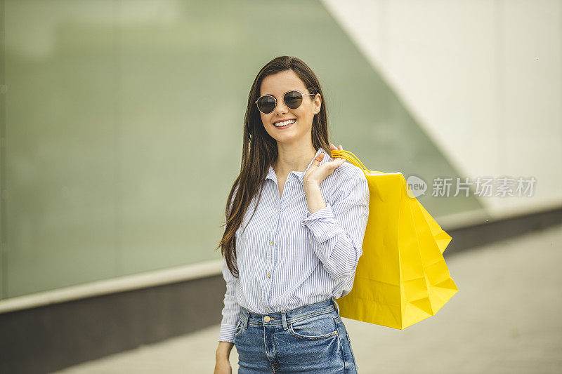 年轻漂亮的女人提着购物袋走路