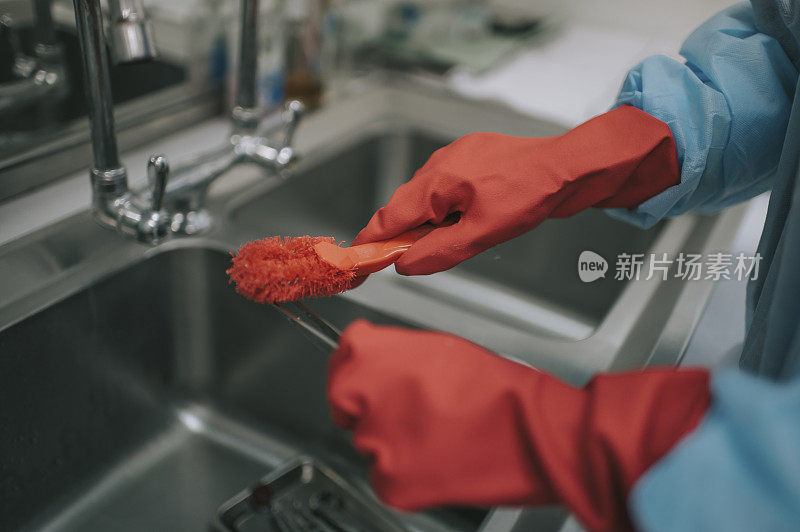 亚洲华裔女护士穿着个人防护服清洁手术工具