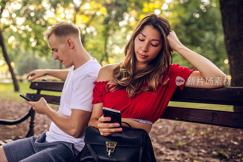 年轻女孩和她的男朋友用智能手机忽视彼此