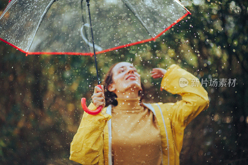 秋雨中带着透明塑料伞的快乐女人