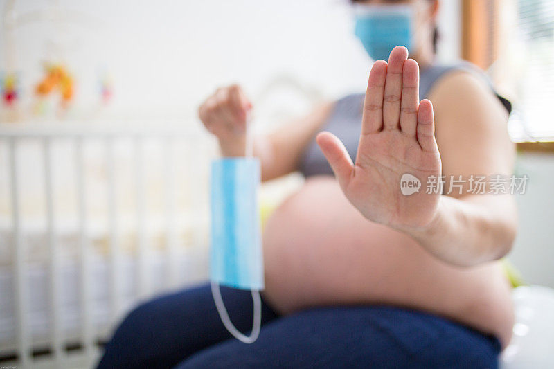 孕妇戴着医用口罩，用手势示意停止