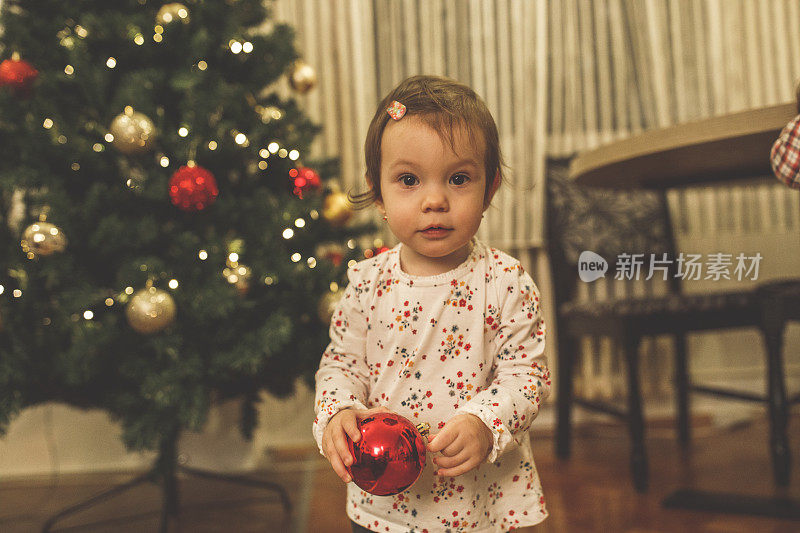 可爱的小女孩带着红色的圣诞装饰品对着镜头微笑