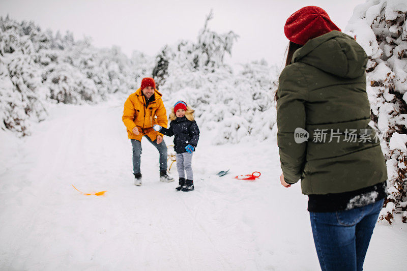 在一个美丽的冬天，年轻快乐的家庭一起在户外玩雪