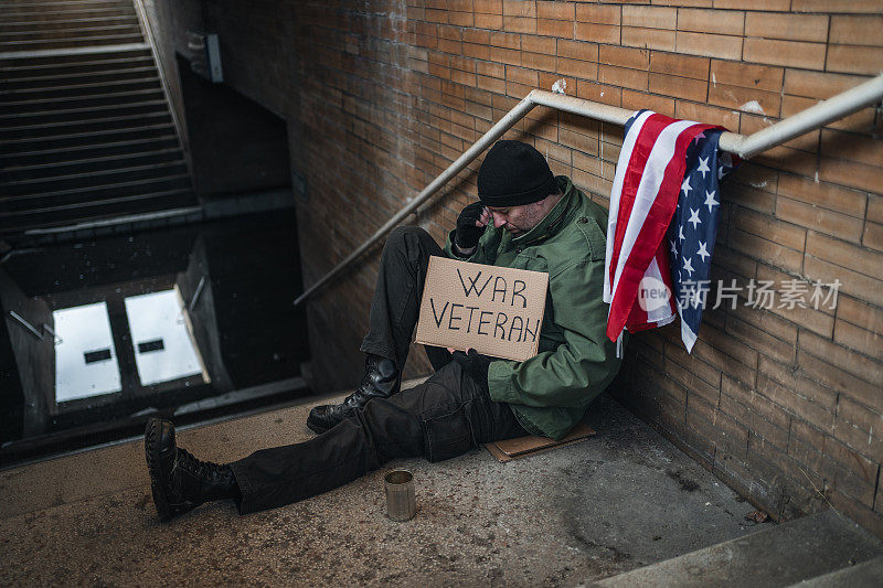 无家可归的退伍军人在街上乞讨，手里拿着一个写着短信的牌子