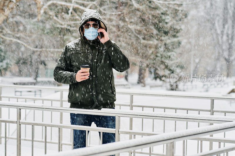 冬天在公园里戴着防护面具和太阳镜打电话的男人
