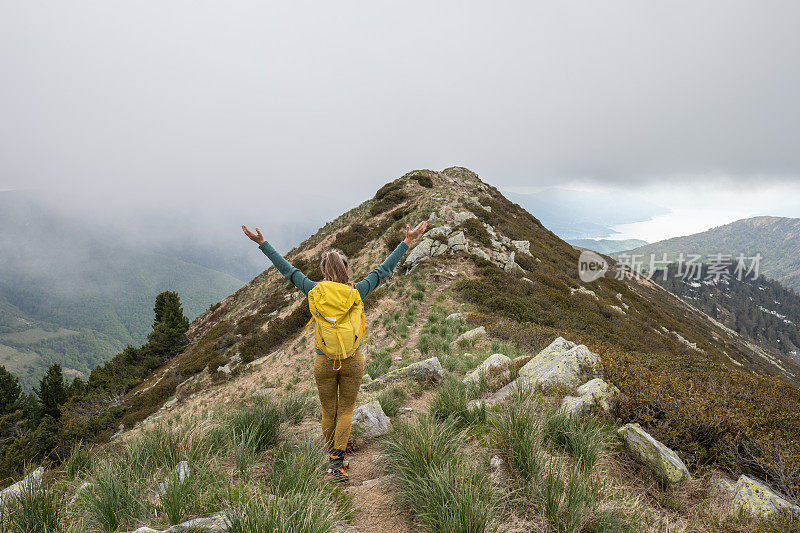 一个徒步旅行者双臂伸开站在山顶上