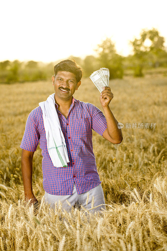 农民在农田里持有印度卢比钞票