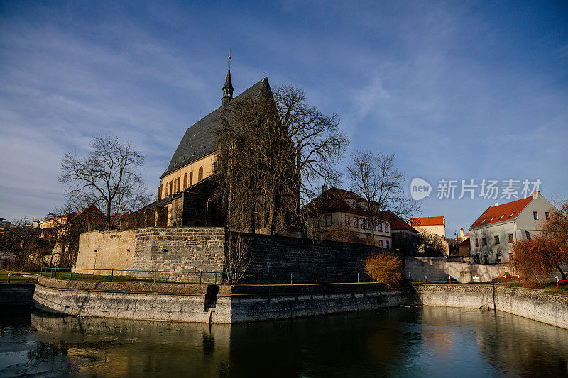 2020年12月27日，捷克共和国，波西米亚中部，中世纪小镇Slany中心，城市防御工事和带有钟楼的哥特式教堂附近的池塘