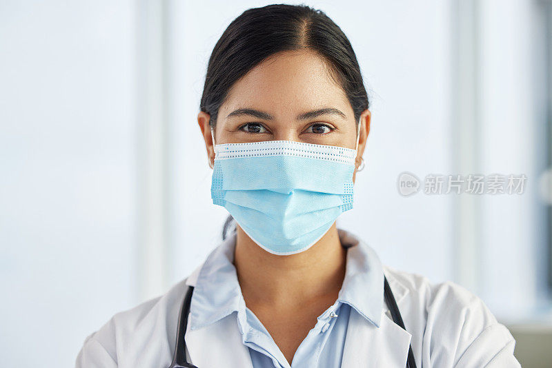 一名医生戴着口罩，白天独自站在诊所里