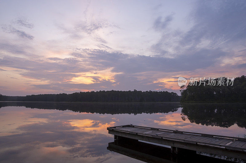 黎明前的云朵笼罩着宁静的湖面和质朴的码头