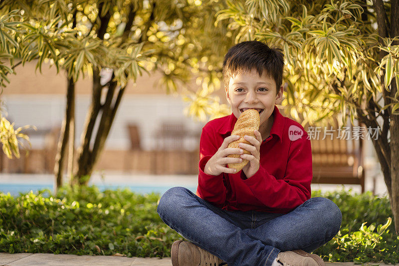 在绿色背景下吃面包的男孩