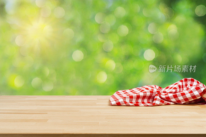 一张铺着皱巴巴的野餐毯子和郁郁葱葱的树叶的桌子