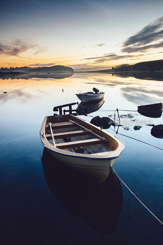 在日出时平静的水面上划着小船