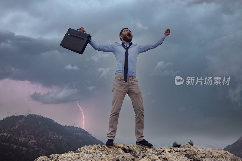 一个年轻的商人在暴风雨的日子里站在山顶上。