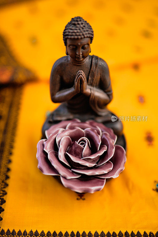 棕色的佛像与紫色的瓷玫瑰在黄色的印度教纱丽刺绣绳