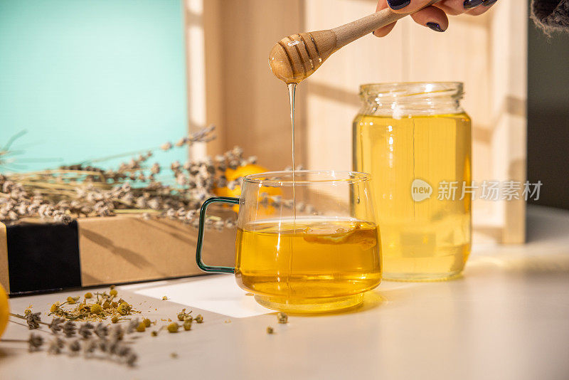 蜂蜜从木制的蜂蜜勺滴入玻璃杯中