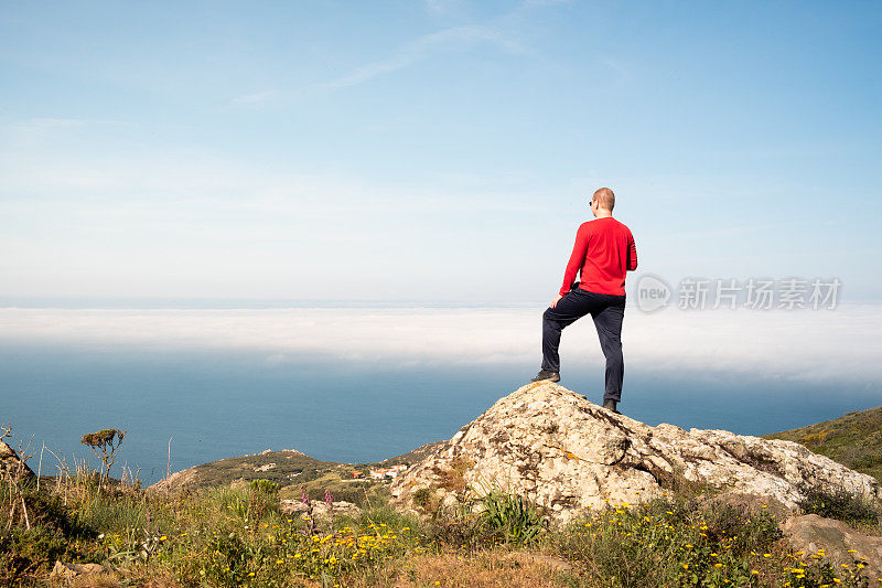 在辛特拉，人们站在山顶上，看着云层上方的大海