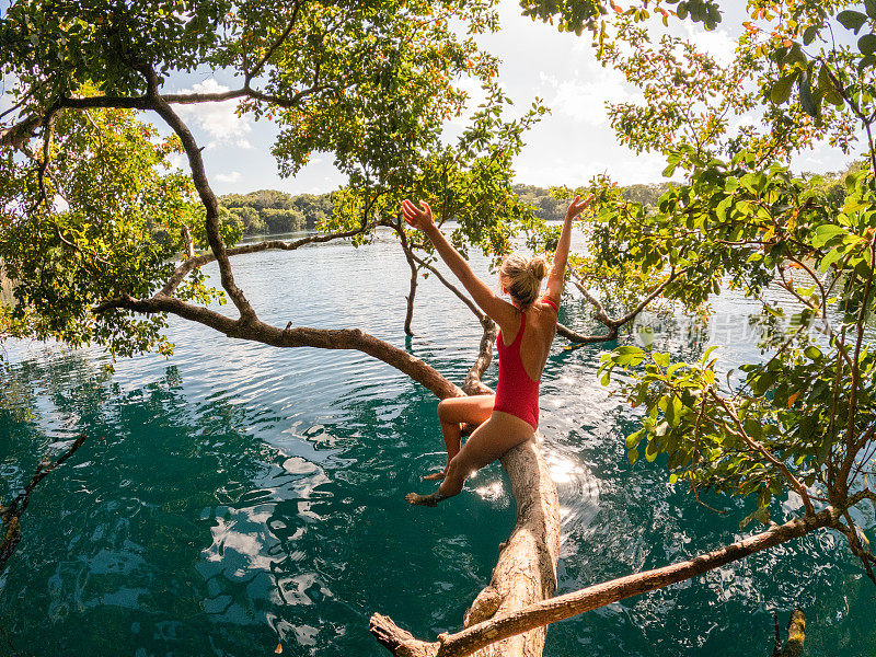 女人在热带天然井的一棵树上放松，尽情享受大自然
