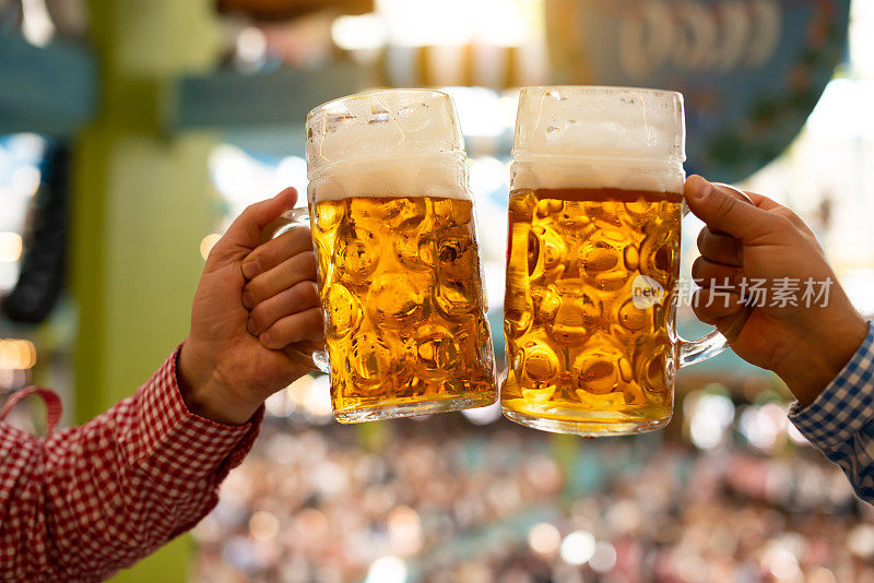 啤酒节上，两个人在啤酒帐篷里用啤酒杯干杯