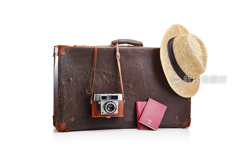一个老式的棕色皮箱，里面装着相机，一顶草帽，两本白色护照。准备好旅行和度假的概念