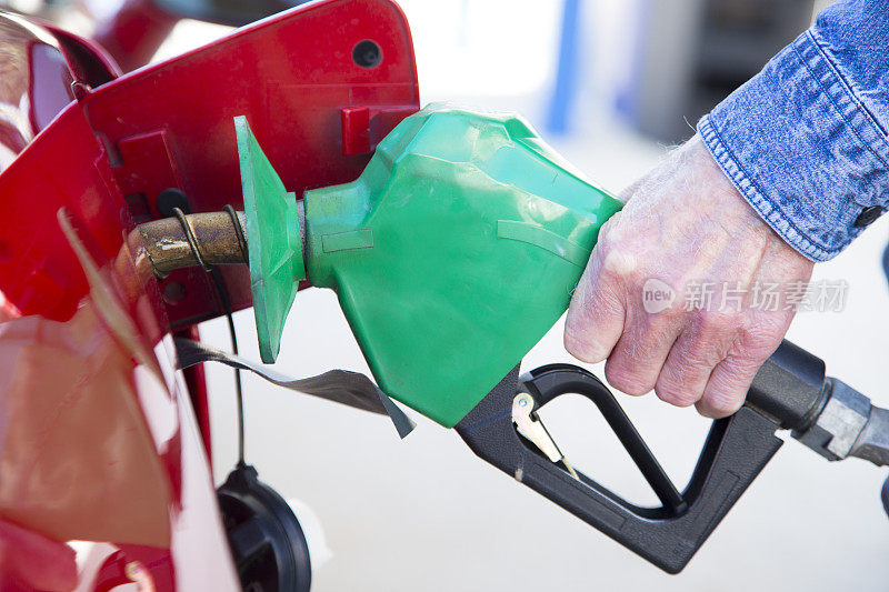通货膨胀导致汽油价格上涨。向车辆泵入汽油。红色的车，绿色的喷嘴。