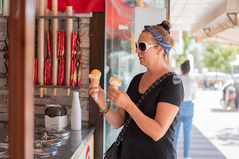 成熟的女人在街上买冰淇淋。