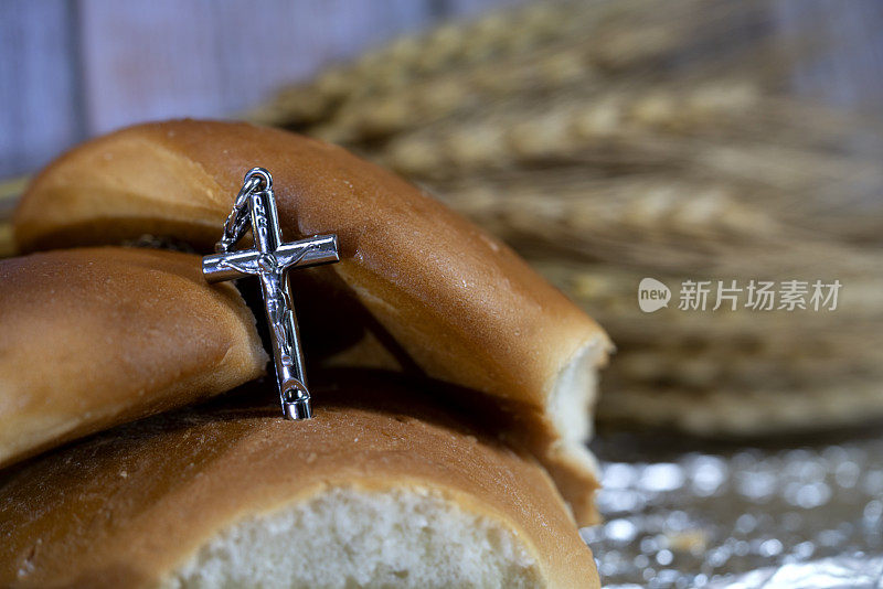 三个面包和银色十字架和模糊的小麦作为背景和灵感