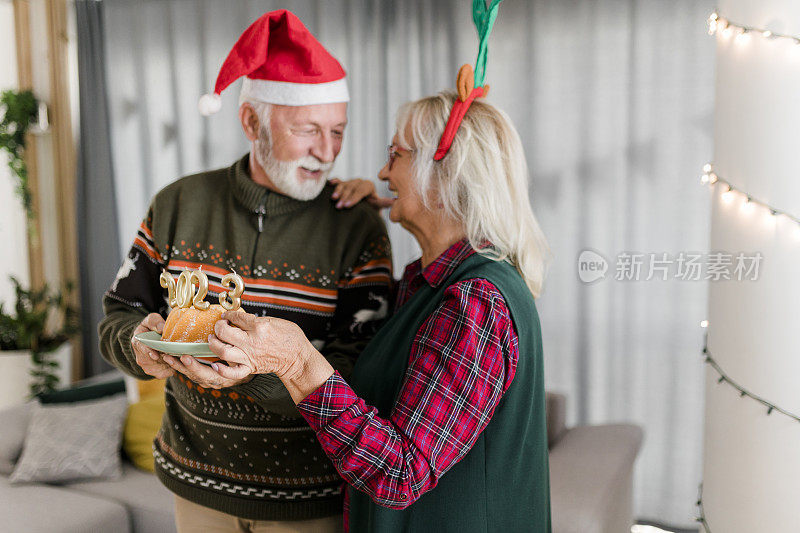 老夫妇在庆祝圣诞节，手里拿着圣诞蛋糕