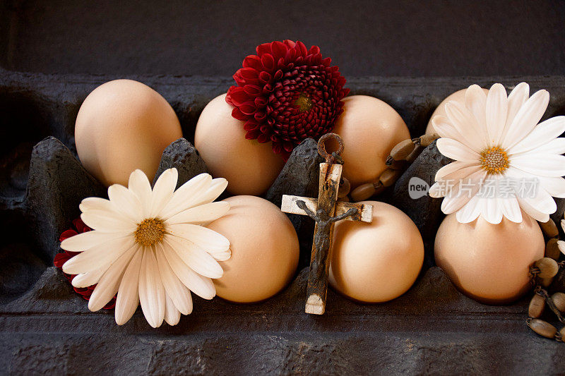 复活节背景的鸡蛋在一个鸡蛋盒与十字架和花。