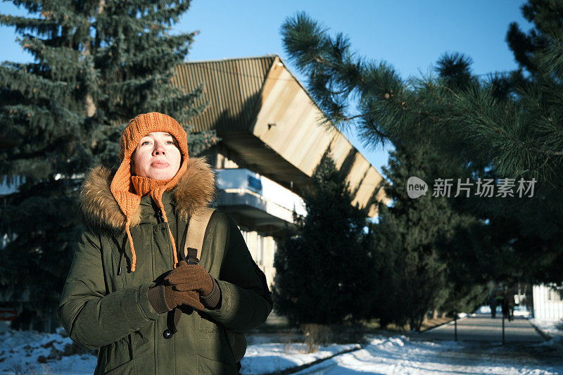 在阳光明媚的冬日小镇的街道上，女人在等人