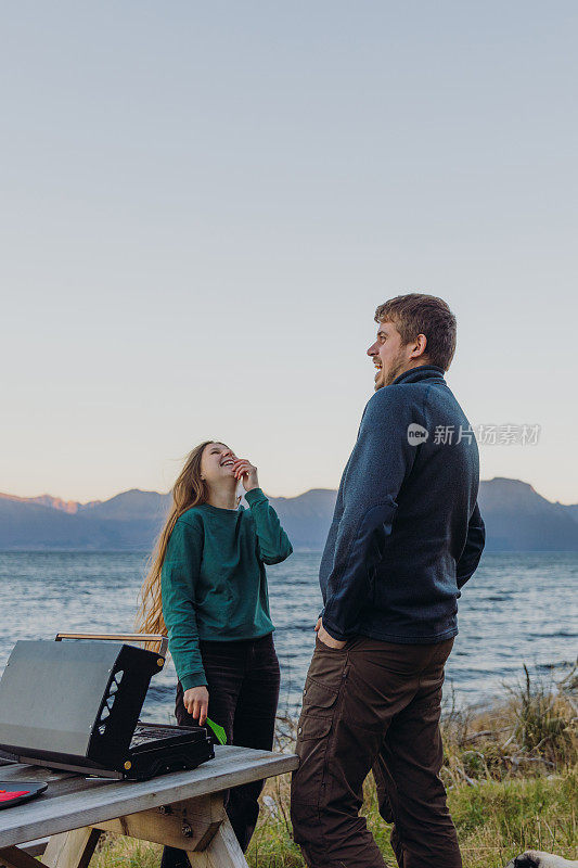 一个女人和一个男人在海边野餐，凝视着快乐的日落时分